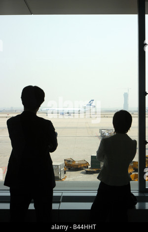 Due persone che guardano all'area lato volo dell'aeroporto di Pechino, Cina Foto Stock