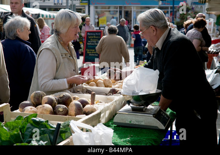 Donna matura l'acquisto di prodotti locali freschi ortaggi di stagione dal commerciante di mercato a Aberystwyth mercato degli agricoltori e il salone del cibo Wales UK Foto Stock
