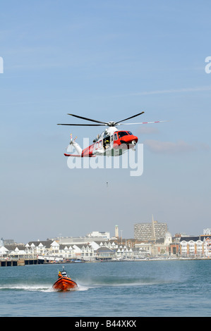 Ricerca e salvataggio della Guardia costiera elicottero su esercizio con una fascia costiera di RNLI scialuppa di salvataggio fuori città Quay in Inghilterra Southampton Regno Unito Foto Stock