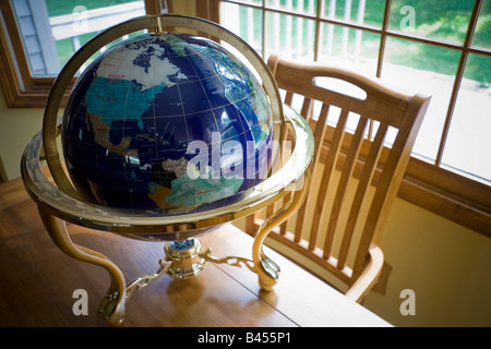 Un globo mondo sulla scrivania con sedia Foto Stock