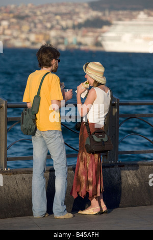 Coppia giovane mangiare un panino di pesce Balik Ekmek a Eminonu Harbourside Istanbul Turchia Foto Stock