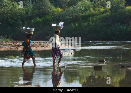 Rurale villaggio indiano donne attraversando il fiume Chitravathi equilibratura di un recipiente di metallo posto sulla loro testa. Puttaparthi, Andhra Pradesh, India Foto Stock