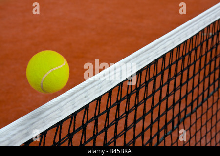 Palla da tennis di scorrimento sul net su clay court Foto Stock