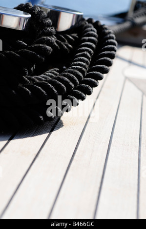 Corda nera sul ponte in teak a bordo di un super yacht. Foto di Patrick patricksteel in acciaio Foto Stock