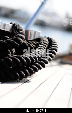 Corda nera sul ponte in teak a bordo di un super yacht. Foto di Patrick patricksteel in acciaio Foto Stock