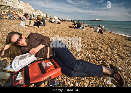 Giovane donna quotidiano di lettura sulla spiaggia di Brighton, Sussex, Inghilterra Foto Stock