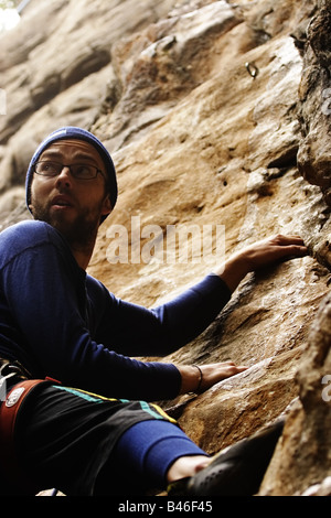 Rocciatore guardando indietro come è leader il passo su una corda fissa salire Foto Stock