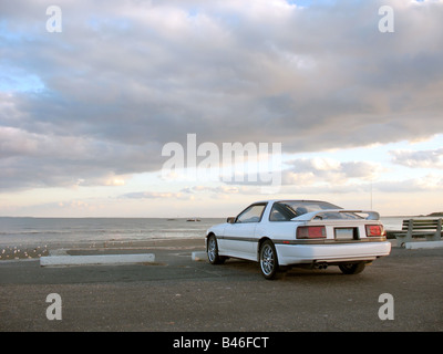 Un bianco personalizzato sport auto parcheggiate in spiaggia Foto Stock