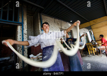 Uyghur uomo rendendo Laghman freschi Tagliatelle al mercato domenicale di Kashgar nella provincia dello Xinjiang in Cina Foto Stock