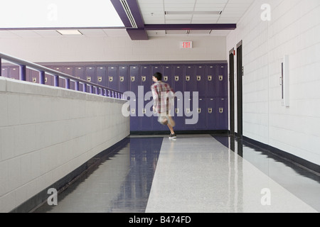 Un maschio di studente di scuola superiore in esecuzione in un corridoio Foto Stock