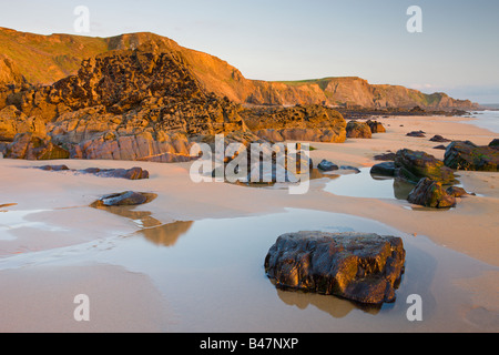 Golden luce della sera illumina un deserto Sandymouth Bay in North Cornwall Inghilterra Foto Stock