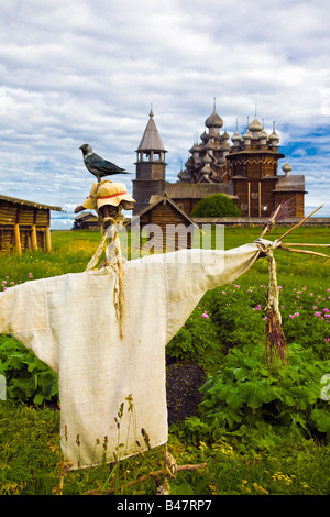 crow sitting on scarecrow with wooden Catherdral in background on Kizhi Island russia Russian Federation Stock Photo