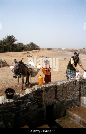 Geografia / viaggi, Marocco, le persone, le ragazze con la loro madre di ottenere acqua a una fontana, Merzouga Erg Chebbi desert, Tafilalt valley, asino, bestia da soma, può, caricato con acqua può, bambini , Additional-Rights-Clearance-Info-Not-Available Foto Stock