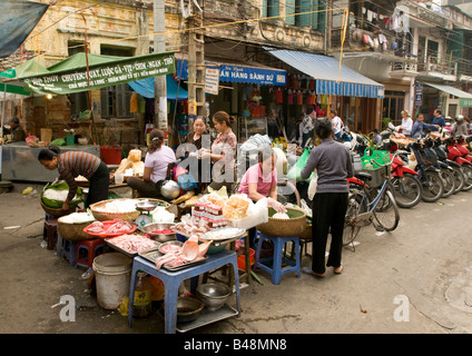 Un affollato di stallo di carne su un angolo di strada nel quartiere vecchio di Hanoi in Vietnam anteriore di una fila di biciclette Foto Stock