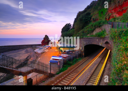 Alba dalla passerella ferroviaria a Dawlish in South Devon con i percorsi di luce di un treno in arrivo fuori del tunnel Foto Stock