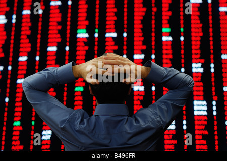 Stock Trader si fermò davanti a un display di grandi dimensioni delle quotazioni di borsa Foto Stock