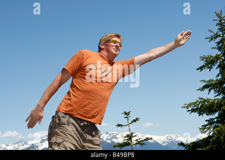 L uomo lo stiro con braccia aperte sulla cima di una montagna in Whistler BC Foto Stock