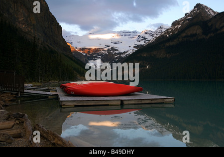 Red canoe e il Ghiacciaio Victoria riflettendo in Lake Louise al Sunrise, il Parco Nazionale di Banff, Alberta, Canada. Foto Stock