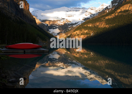 Red canoe e il Ghiacciaio Victoria riflettendo in Lake Louise al Sunrise, il Parco Nazionale di Banff, Alberta, Canada. Foto Stock