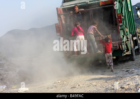I bambini a cavallo di un cassonetto in Sharre, una delle baraccopoli accanto a una discarica alla periferia di Tirana, Albania Foto Stock