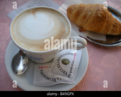 Cappuccino e croissant serviti sulla tovaglia rosa in Roma, Italia Foto Stock