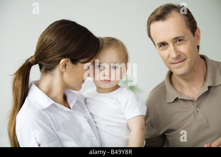 Uomo accanto a moglie e bambino, sorridente in telecamera Foto Stock