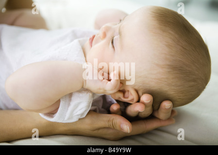 Bambino giacente su madre le mani, ritagliato Foto Stock