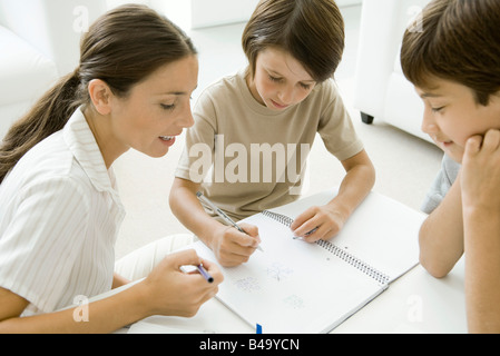 Madre e due figli giocare tic-tac-toe insieme Foto Stock