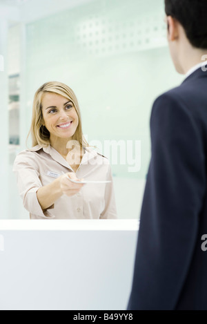 Professional donna in piedi dietro il bancone, consegna documento a imprenditore Foto Stock