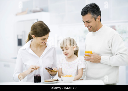 I genitori e la giovane figlia prepara la colazione in cucina Foto Stock