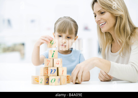 Bambina blocchi di impilamento, madre guarda e sorridente Foto Stock