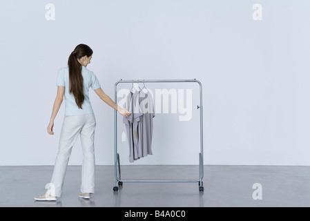 Donna che guarda al tee-shirts appeso sul rack, vista posteriore Foto Stock