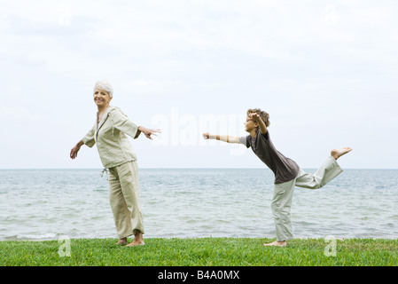 Senior donna si allunga come nipote saldi in piedi su una gamba Foto Stock