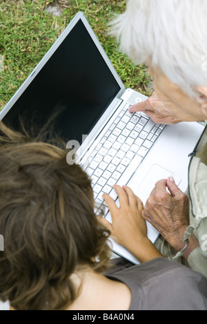 Senior donna seduta con il nipote guardando al computer portatile insieme Foto Stock