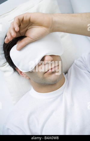 L'Uomo sdraiato con occhio maschera, mano sulla testa Foto Stock