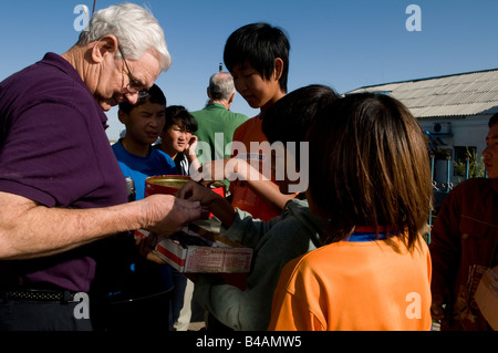 Passeggeri stranieri comprare souvenir da bambini mongola su una piattaforma di una mongola stazione ferroviaria Foto Stock