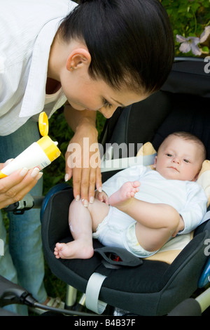 La mamma mette sun-crema sul corpo del bambino Foto Stock