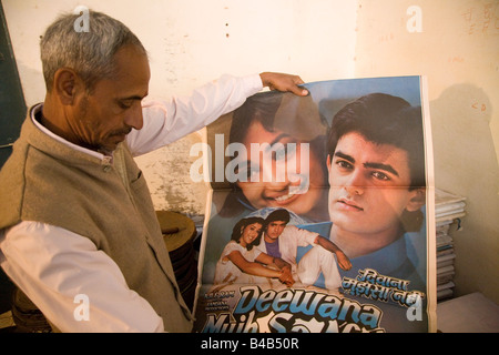 Un uomo tiene fuori un film di Bollywood poster in un film ai distributori di Varanasi (India). Foto Stock