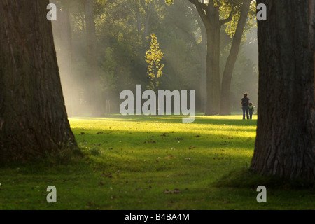 Donna madre e bambino prato a piedi nel parco Kralingse in serata sotto la mellow calda luce colonne natura Rotterdam Paesi Bassi Foto Stock