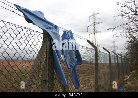 Tangled abbigliamento appeso su "Filo spinato" scherma sotto un terrapieno accanto alla A13 strada in Dagenham Essex Foto Stock