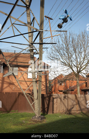 Le travi in acciaio di un traliccio di elettricità con intrappolato triciclo sorge vicino tra l'alloggiamento su un break in Beckton, East London Foto Stock