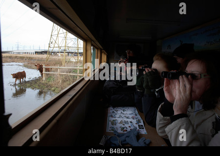 Peer Birdspotters attraverso il binocolo in un nascondere alla RSPB's bird e riserva naturale a Rainham paludi, Essex Foto Stock