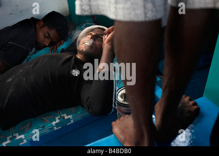 Un equipaggio maldiviano riposare prima di una giornata di tonno albacora la pesca a bordo di un tradizionale dhoni barca da pesca sull'Oceano Indiano Foto Stock