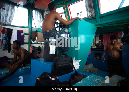 Un equipaggio maldiviano riposare prima di una giornata di tonno albacora la pesca a bordo di un tradizionale dhoni barca da pesca sull'Oceano Indiano Foto Stock