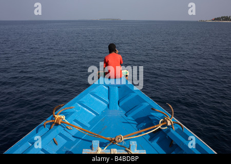 Un crewman maldiviano utilizza un telefono cellulare dopo una giornata di pesca al tonno a bordo di un dhoni barca da pesca in una zona remota dell Oceano Indiano Foto Stock