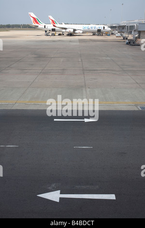 Due frecce dipinte di stencil sul piazzale aeromobili dell aeroporto di Colombo puntano in direzioni opposte Foto Stock