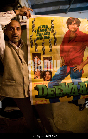 Un uomo tiene fuori un poster pubblicitari un Amitabh Bachchan film in un film ai distributori di Varanasi (India). Foto Stock