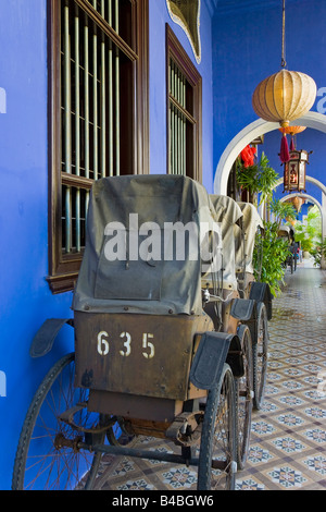 Asia, Malaysia, Penang Pulau Pinang, Georgetown, quartiere Chinatown, dettaglio di Trishaws schierate contro un azzurro parete dipinta Foto Stock