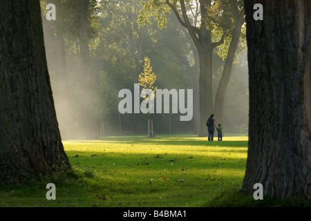 Donna madre e bambino prato a piedi nel parco Kralingse in serata sotto la mellow calda luce colonne natura Rotterdam Paesi Bassi Foto Stock
