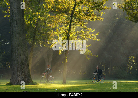 Due uomini a cavallo in bicicletta Kralingse park in serata sotto la mellow calda luce colonne natura sport Rotterdam Paesi Bassi Foto Stock